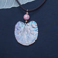 Gargantilla artesanal de cobre electroformado con hoja del árbol del amor, jaspe rosado y pátina multicolor sobre cordón marrón